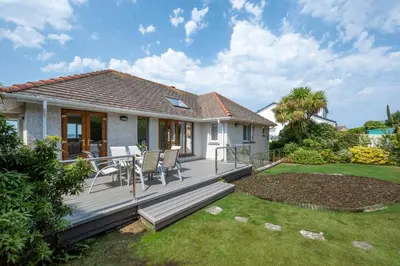 a wooden deck with a table and chairs in a yard at 4 Bed in Marazion oc-gwynsa in Marazion