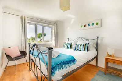 a bedroom with a bed with a chair and a window at 4 Bed in Marazion oc-gwynsa in Marazion