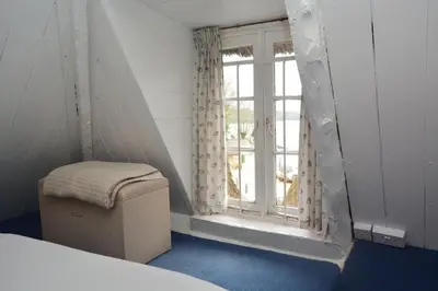a bedroom with a window and a stool in front of it at 3 Bed in Helford oc-hcmimo in Helford