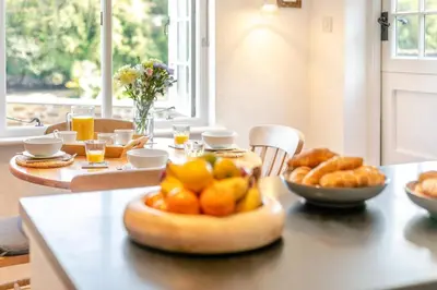 a table with a bowl of oranges and bread on it at 2 Bed in Helford oc-hcpopi in Helford