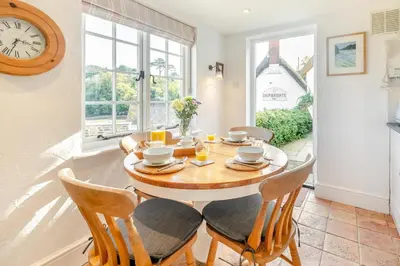 a dining room with a table and chairs and a clock at 2 Bed in Helford oc-hcpopi in Helford