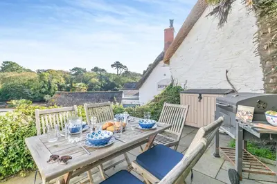 a table and chairs on the patio of a cottage at 2 Bed in Helford oc-hcpopi in Helford