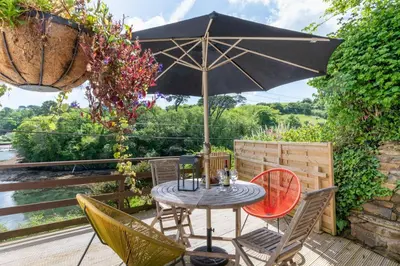 a table and chairs with an umbrella on a deck at 2 Bed in Helford oc-hcview in Helford