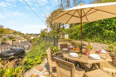 a wooden table with an umbrella and a grill at 3 Bed in Helford oc-hcwedn in Helford