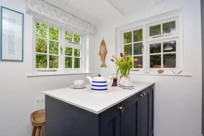a kitchen with a white counter and two windows at 3 Bed in Helford oc-hcwell in Helford