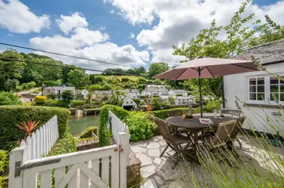 a wooden table with an umbrella in a garden at 3 Bed in Helford oc-hcwell in Helford