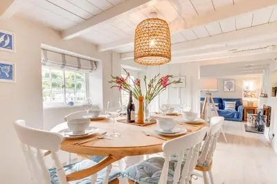 a dining room with a wooden table and white chairs at 3 Bed in Helford oc-hcwell in Helford