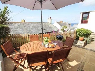 a wooden table with chairs and an umbrella on a patio at 3 Bed in Porthleven oc-ingnoo in Porthleven