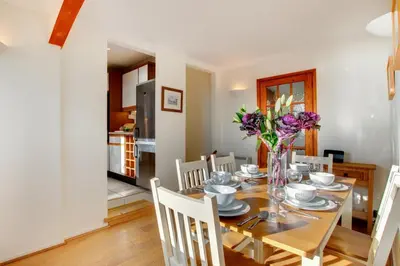 a dining room with a table with a vase of flowers at 3 Bed in Porthleven oc-ingnoo in Porthleven