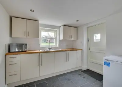 a kitchen with white cabinets and a sink and a window at 2 Bed in Breage oc-jobcot in Breage