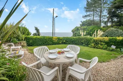 a white table and chairs on a patio with the ocean at 2 Bed in Looe oc-l00055 in Trelaske