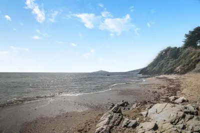 a beach with rocks and the ocean on a sunny day at 2 Bed in Looe oc-l00055 in Trelaske