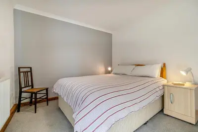 a white bedroom with a bed and a chair at 2 Bed in Looe oc-l00055 in Trelaske