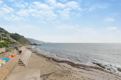 a beach with umbrellas and the ocean on a cloudy day at 1 Bed in Looe oc-l00063 in Trelaske