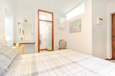 a white bedroom with a bed and a window at 1 Bed in Looe oc-l00063 in Trelaske