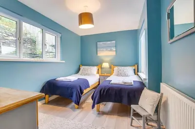 two beds in a room with blue walls and windows at 2 Bed in Looe oc-l10082 in Looe
