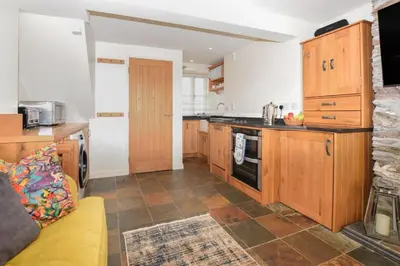 a kitchen with wooden cabinets and a yellow couch at 3 Bed in Looe oc-l10098 in Looe