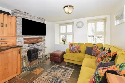 a living room with a yellow couch and a fireplace at 3 Bed in Looe oc-l10098 in Looe