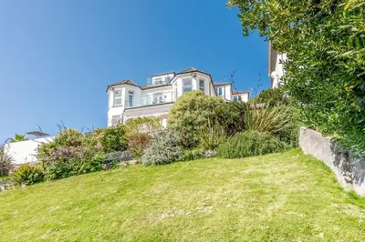 a large white house on a hill with green grass at 1 Bed in Looe oc-l30006 in Looe