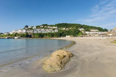 a rock on the beach with houses in the background at 1 Bed in Looe oc-l30006 in Looe
