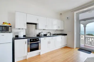 a kitchen with white cabinets and a large window at 1 Bed in Looe oc-l30006 in Looe