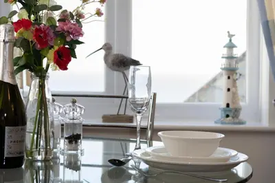 a bird sitting on a glass table with a vase of flowers at 1 Bed in Looe oc-l30008 in Looe
