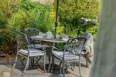 a table with four chairs and an umbrella at 2 Bed in Looe oc-l30015 in Lansallos