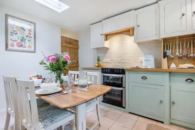 a kitchen with white cabinets and a table and chairs at 2 Bed in Looe oc-l30015 in Lansallos