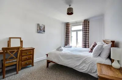 a bedroom with a bed and a dresser and a window at 2 Bed in Looe oc-l30035 in Looe