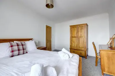 a bedroom with a white bed and a desk and a table at 2 Bed in Looe oc-l30035 in Looe