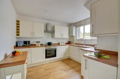 a white kitchen with wooden floors and white cabinets at 2 Bed in Looe oc-l30035 in Looe