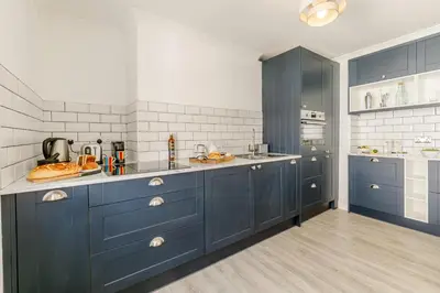 a large kitchen with blue cabinets and white appliances at 1 Bed in Looe oc-l30038 in Looe