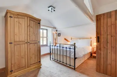 a bedroom with a bed and a large wooden cabinet at 4 Bed in Looe oc-l30047 in Looe