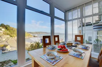 a dining room with a table with a view of the ocean at 4 Bed in Looe oc-l30051 in Looe