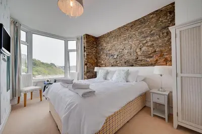 a bedroom with a large bed and a brick wall at 4 Bed in Looe oc-l30051 in Looe
