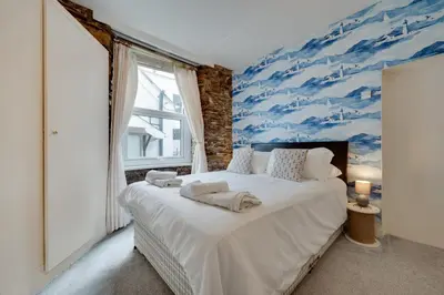 a bedroom with a large bed with a blue painting on the wall at 4 Bed in Looe oc-l30051 in Looe