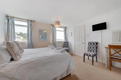 a bedroom with a large white bed and a television at 4 Bed in Looe oc-l30051 in Looe