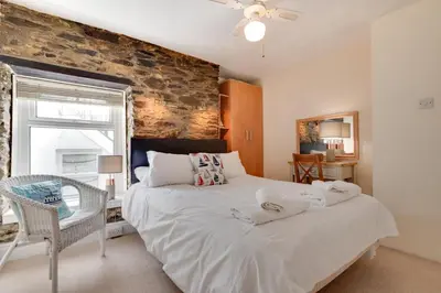 a bedroom with a large bed and a brick wall at 4 Bed in Looe oc-l30051 in Looe