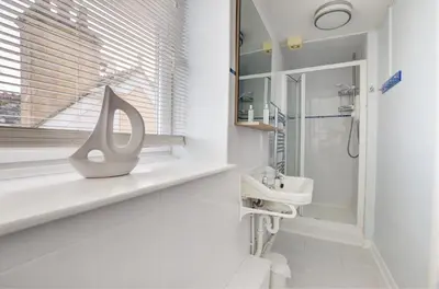 a white bathroom with a sink and a mirror at 4 Bed in Looe oc-l30051 in Looe