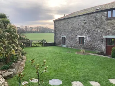 a stone house with a green lawn in front of it at The parlour in Bodmin