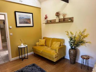 a living room with a yellow couch and a vase with flowers at The parlour in Bodmin