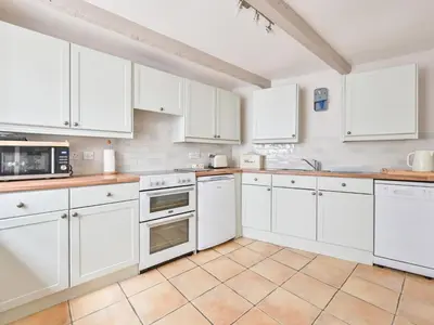 a white kitchen with white cabinets and appliances at Holiday Home Mariners Rest by Interhome in Mevagissey