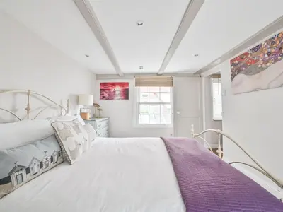 a white bedroom with a bed and a window at Holiday Home Mariners Rest by Interhome in Mevagissey