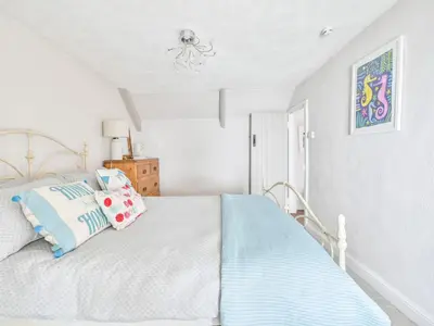 a bedroom with a bed with blue and white sheets at Holiday Home Mariners Rest by Interhome in Mevagissey