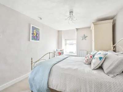 a white bedroom with a bed with a blue blanket at Holiday Home Mariners Rest by Interhome in Mevagissey