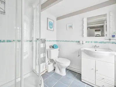 a white bathroom with a toilet and a sink at Holiday Home Mariners Rest by Interhome in Mevagissey