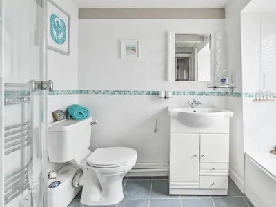 a white bathroom with a toilet and a sink at Holiday Home Mariners Rest by Interhome in Mevagissey