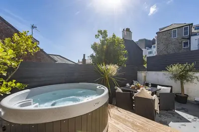 a jacuzzi tub on a deck in a backyard at Azenor House - Central Location - Hot Tub - Free Parking & WiFi - 3 Pets Accepted in St Ives