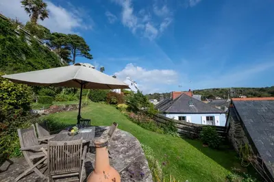 a patio with an umbrella and a table and chairs at 3 Bed in Fowey oc-litin in Fowey