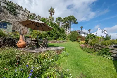 a table with an umbrella in a garden at 3 Bed in Fowey oc-litin in Fowey